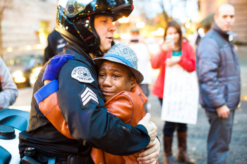 24. Police officer hugs a 12 year old boy following a demonstration for Michael Brown