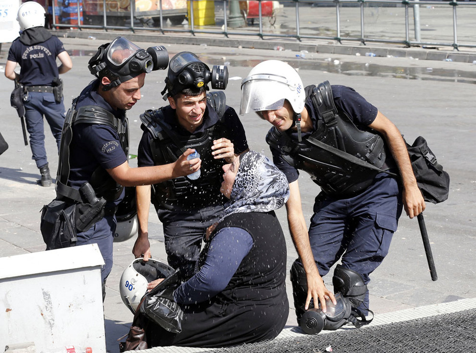 7. Riot police helps a woman affceter by tear gas