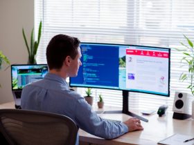 man in gray dress shirt sitting on chair in front of computer monitor