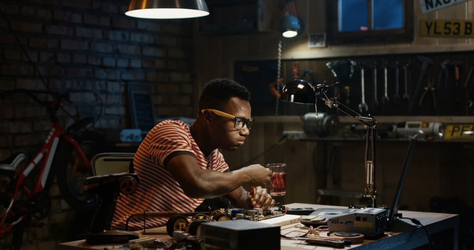Person working on a project at a lit workbench inside a remodeled home garage