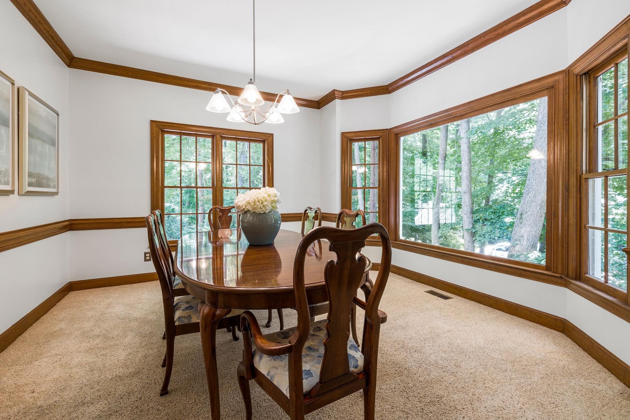 A traditional dining room with a wooden table and chairs on soft low-pile carpet