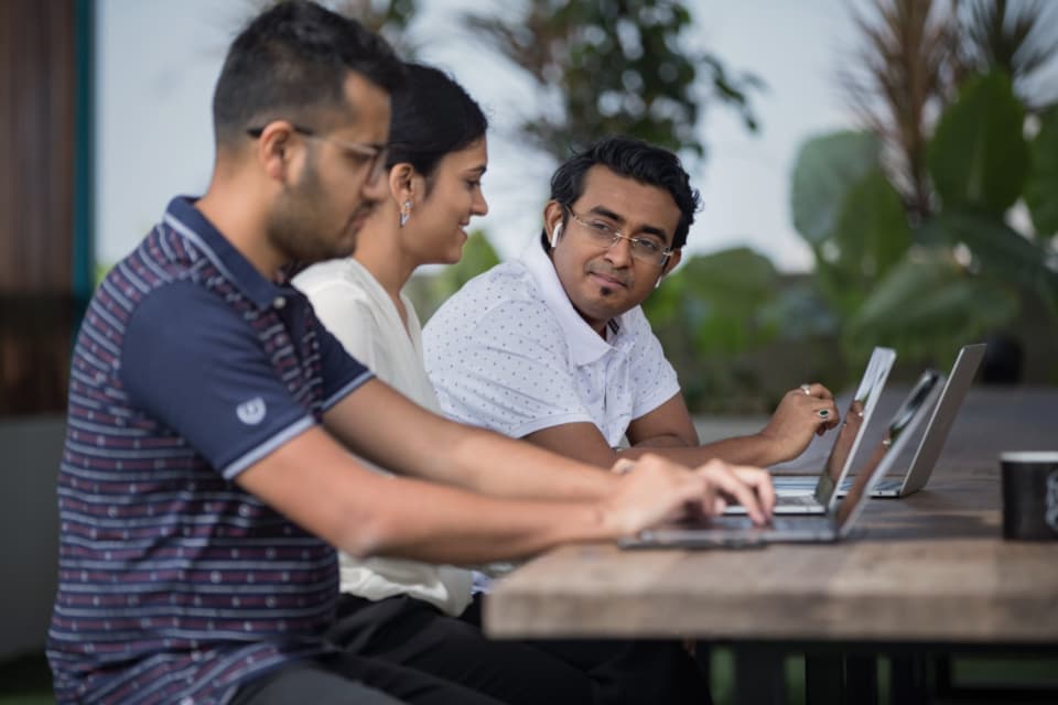 Three colleagues working together on laptops at a shared table