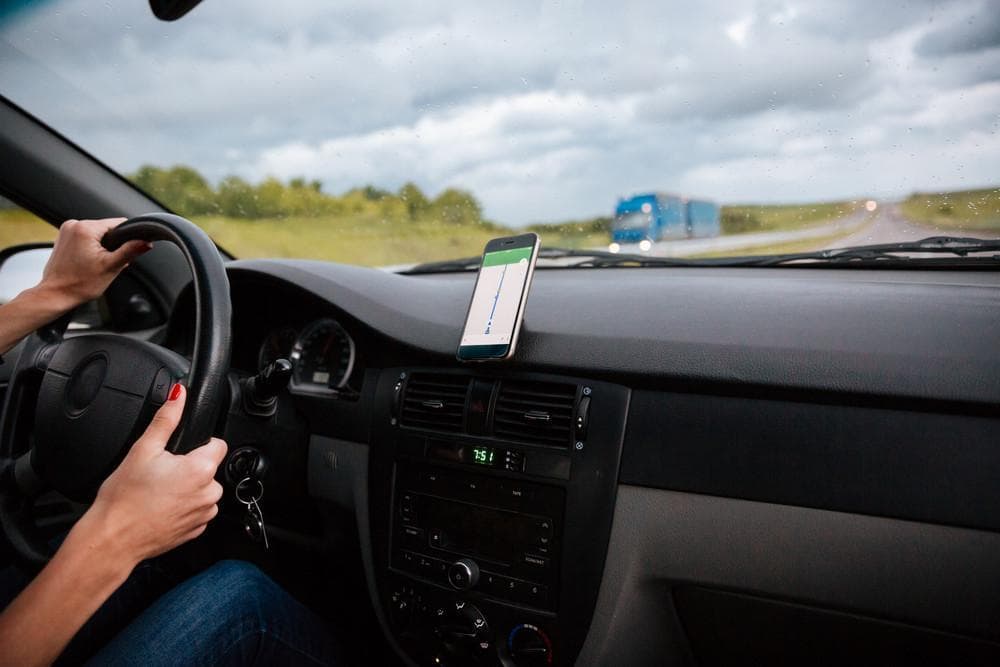 Driver on a highway with a navigation app mounted on the dashboard