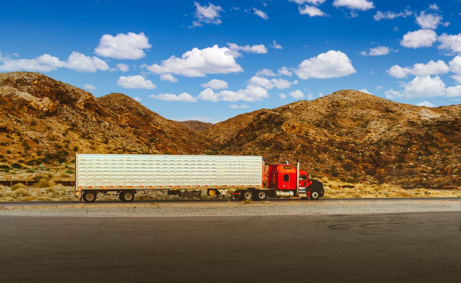 Long-haul semi truck traveling an interstate highway through desert mountains