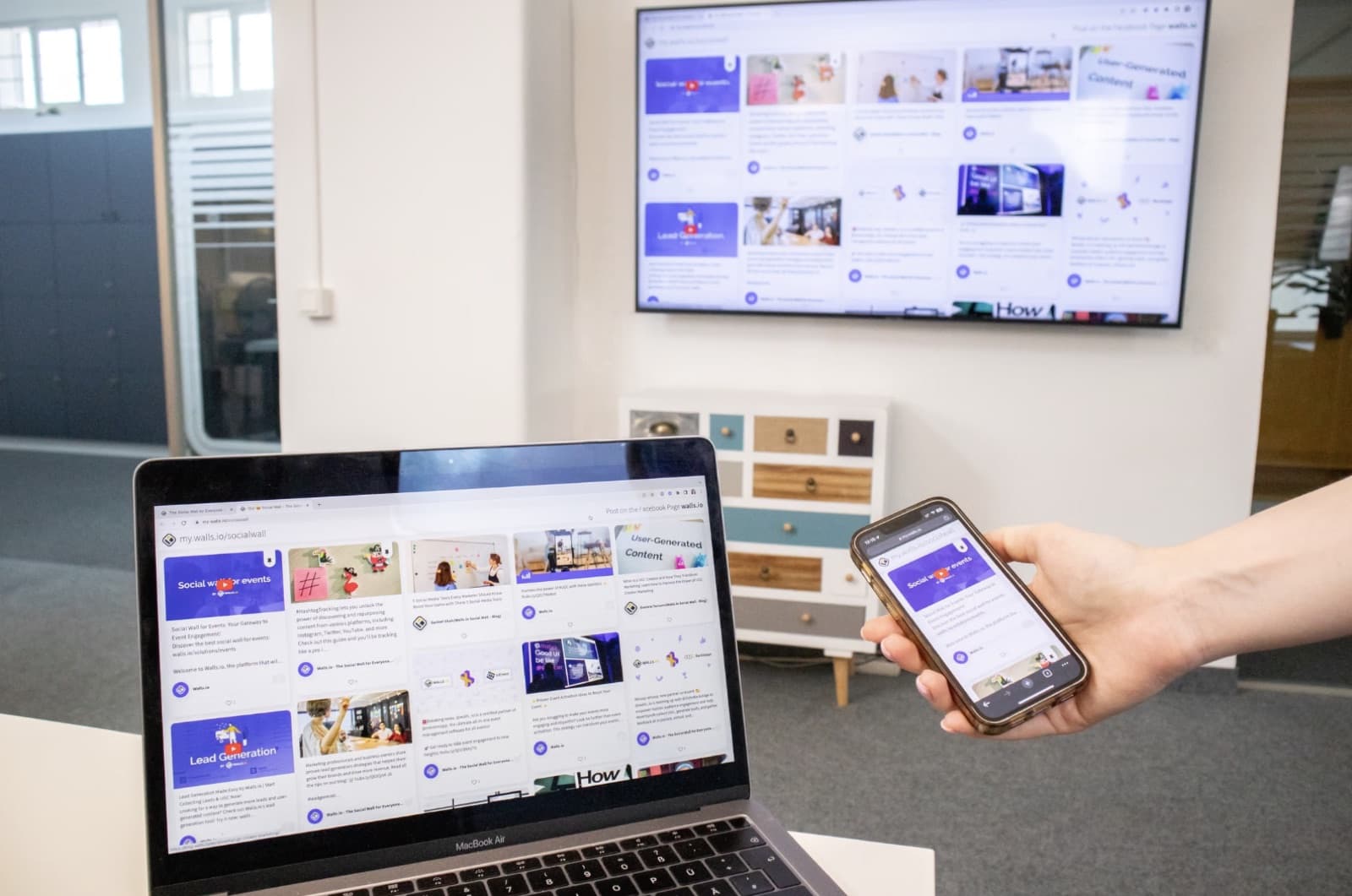 Laptop and phone used as second screens next to a wall-mounted TV