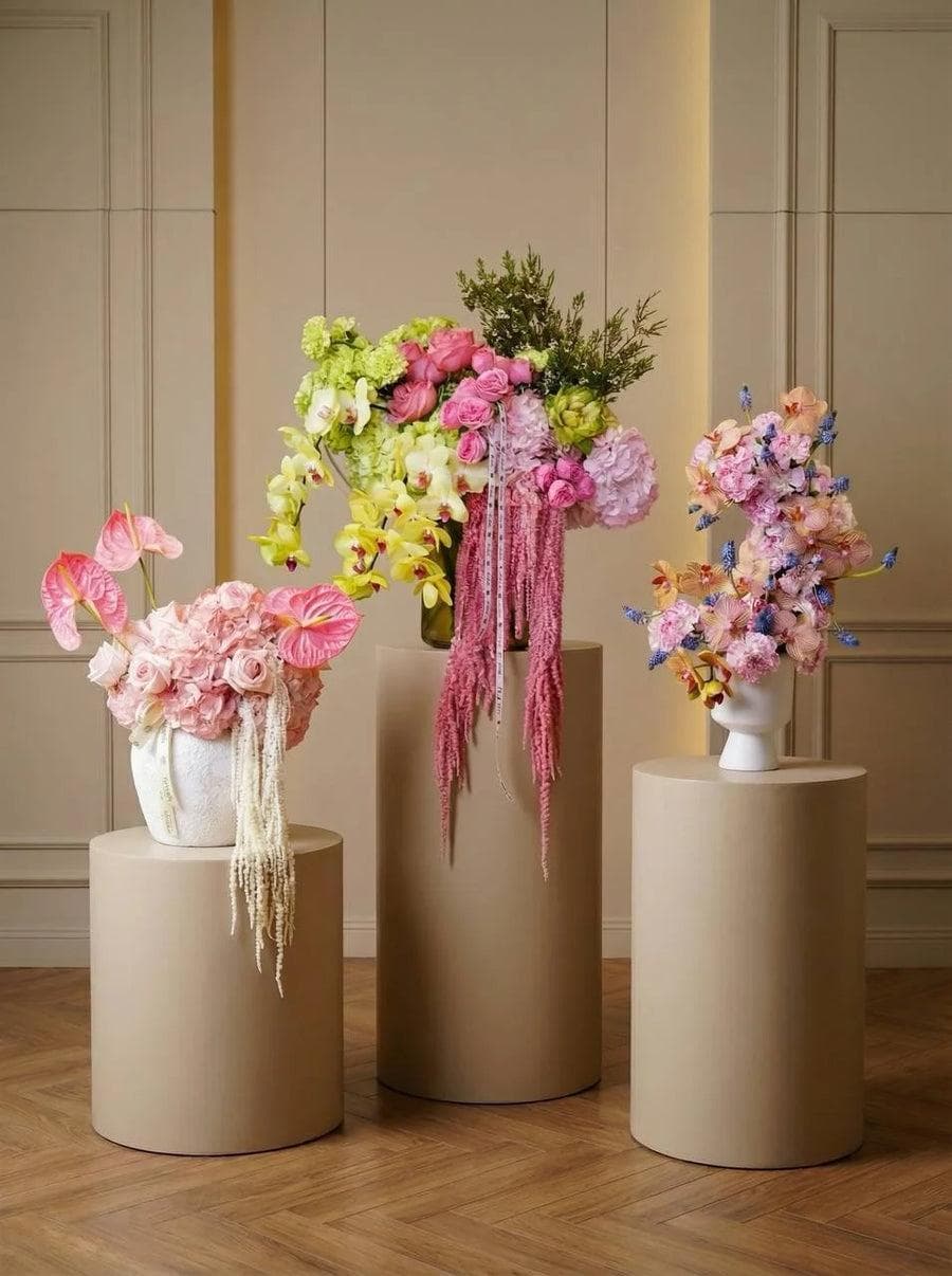 Three floral arrangements on beige pedestals in an elegant room