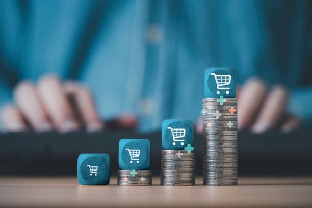 Shopping cart blocks on rising stacks of coins representing ecommerce growth