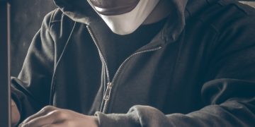 a person wearing a mask using a laptop