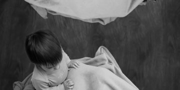 grayscale photo of woman carrying baby