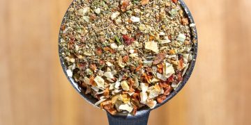 a metal spoon filled with granola on top of a wooden table