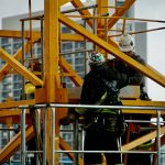 man in black jacket and helmet climbing orange ladder