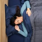 a woman is sleeping in a bed with a blue comforter