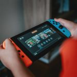 person holding black and orange nintendo switch