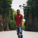 man in red shirt and blue distress denim jeans standing in middle of road