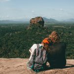 man and woman sitting beside cliff