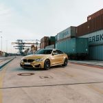 yellow BMW sedan parked near containers during daytime