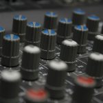 a close up of a sound board with many knobs