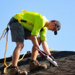 a man in a yellow shirt is working on a roof
