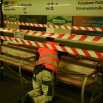 a man in an orange safety vest working on a bench