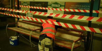a man in an orange safety vest working on a bench