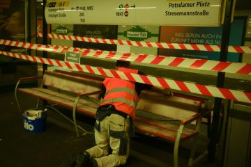 a man in an orange safety vest working on a bench