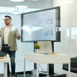 Man presenting data on a large screen to colleagues.