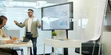 Man presenting data on a large screen to colleagues.