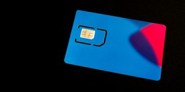 A blue sim card sits on a dark surface.