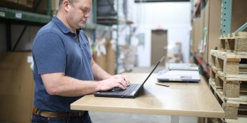 man in blue polo shirt using laptop computer