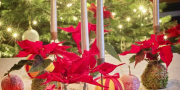 a table topped with apples and candles next to a christmas tree