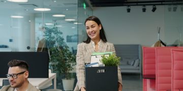Woman carrying box of belongings leaving office