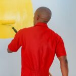 a man painting a wall with yellow paint