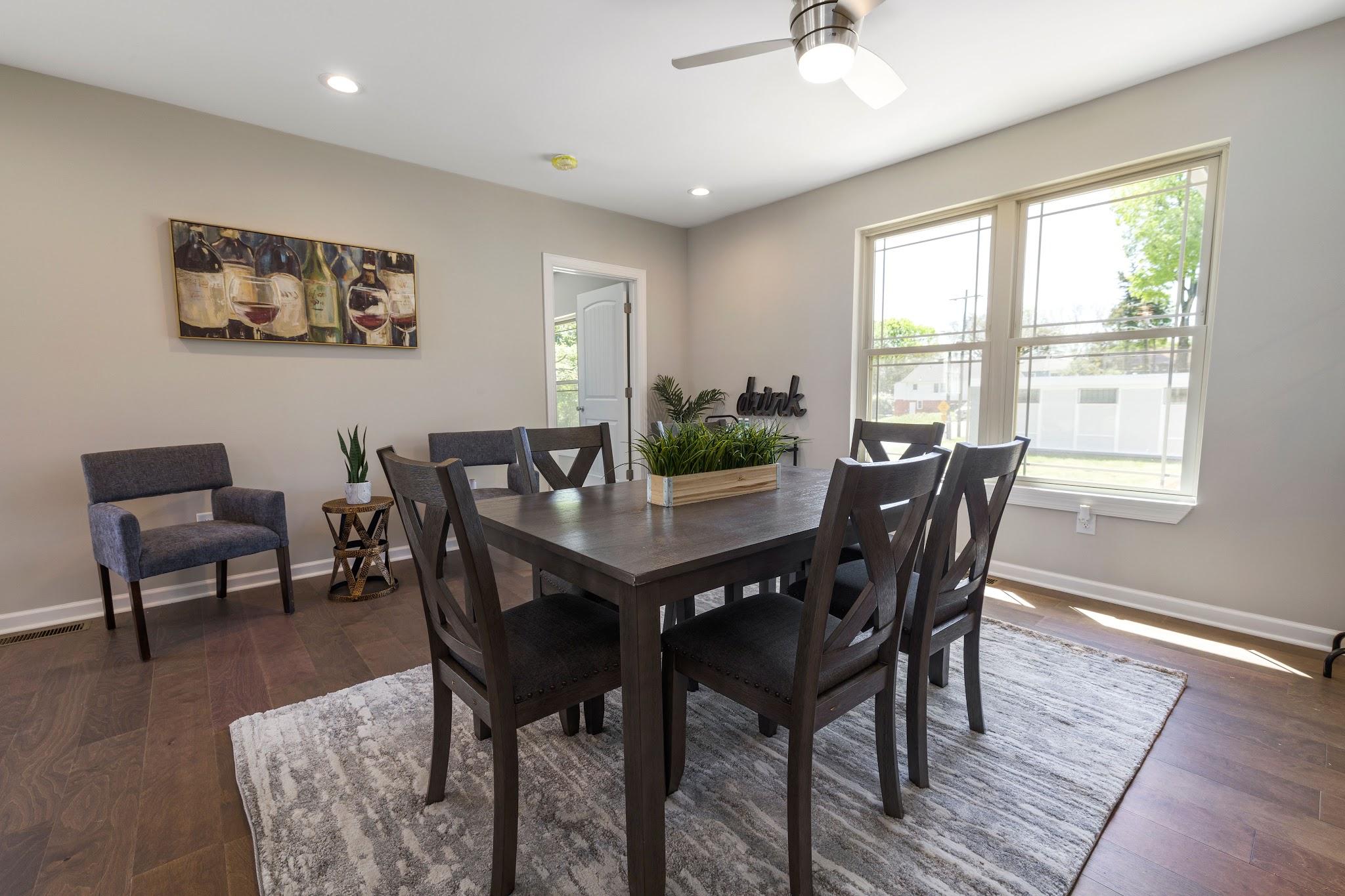A modern dining room with a dark wood table on a low-pile area rug over hardwood floors